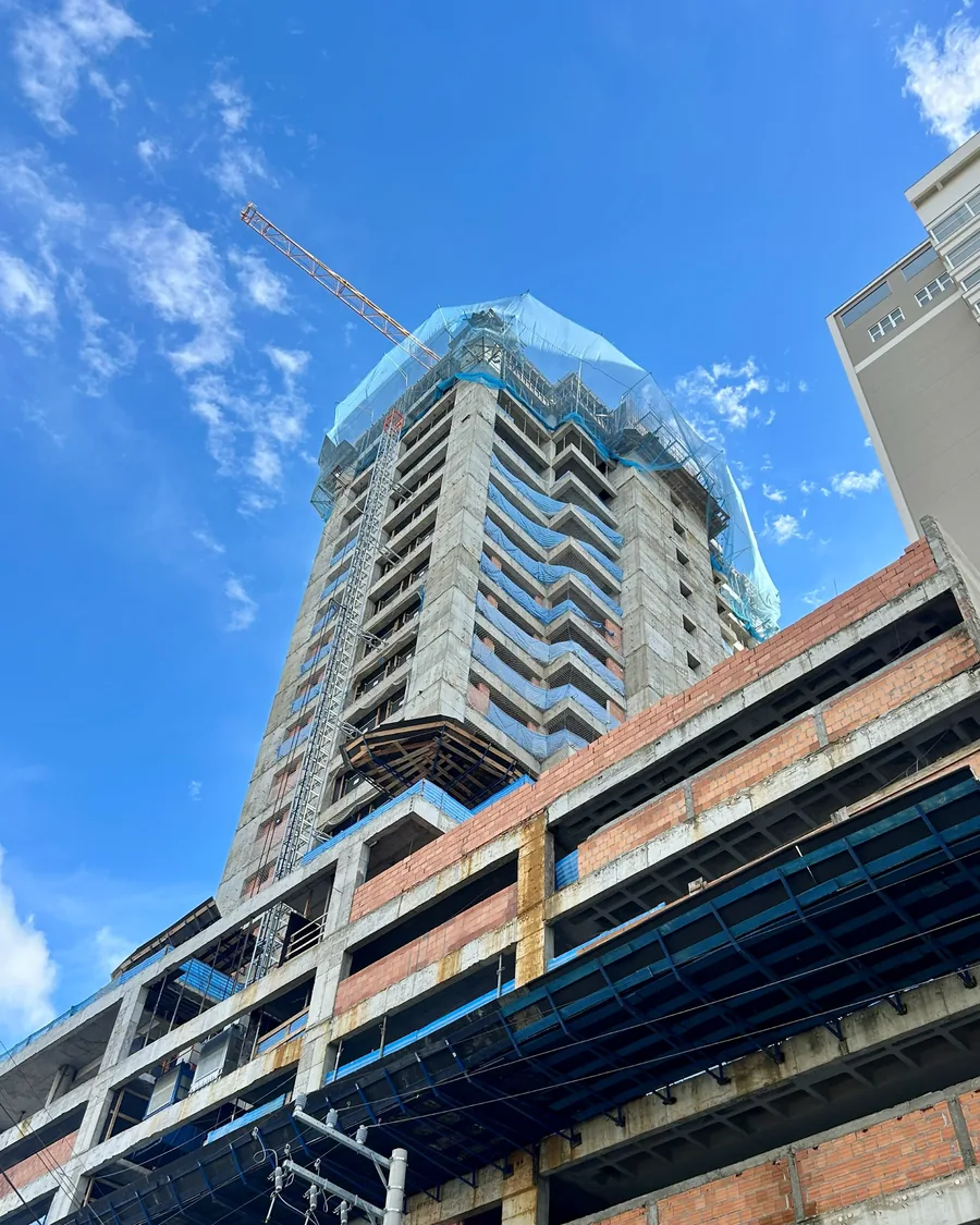 Torre residencial em execução, com grua e bandejas de proteção nos pavimentos