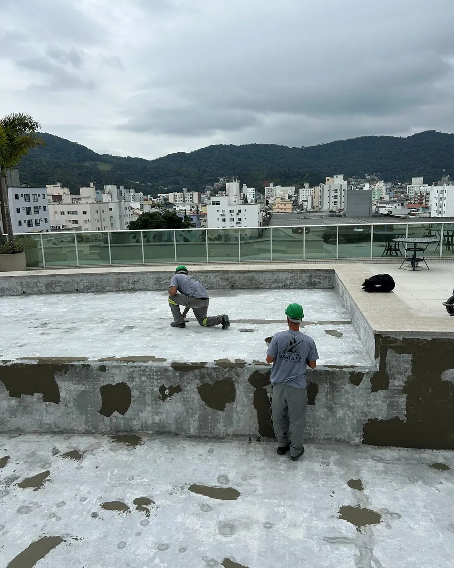 Dois colaboradores da Santa Fé executando manutenção no revestimento de uma piscina drenada, na área de lazer de uma cobertura